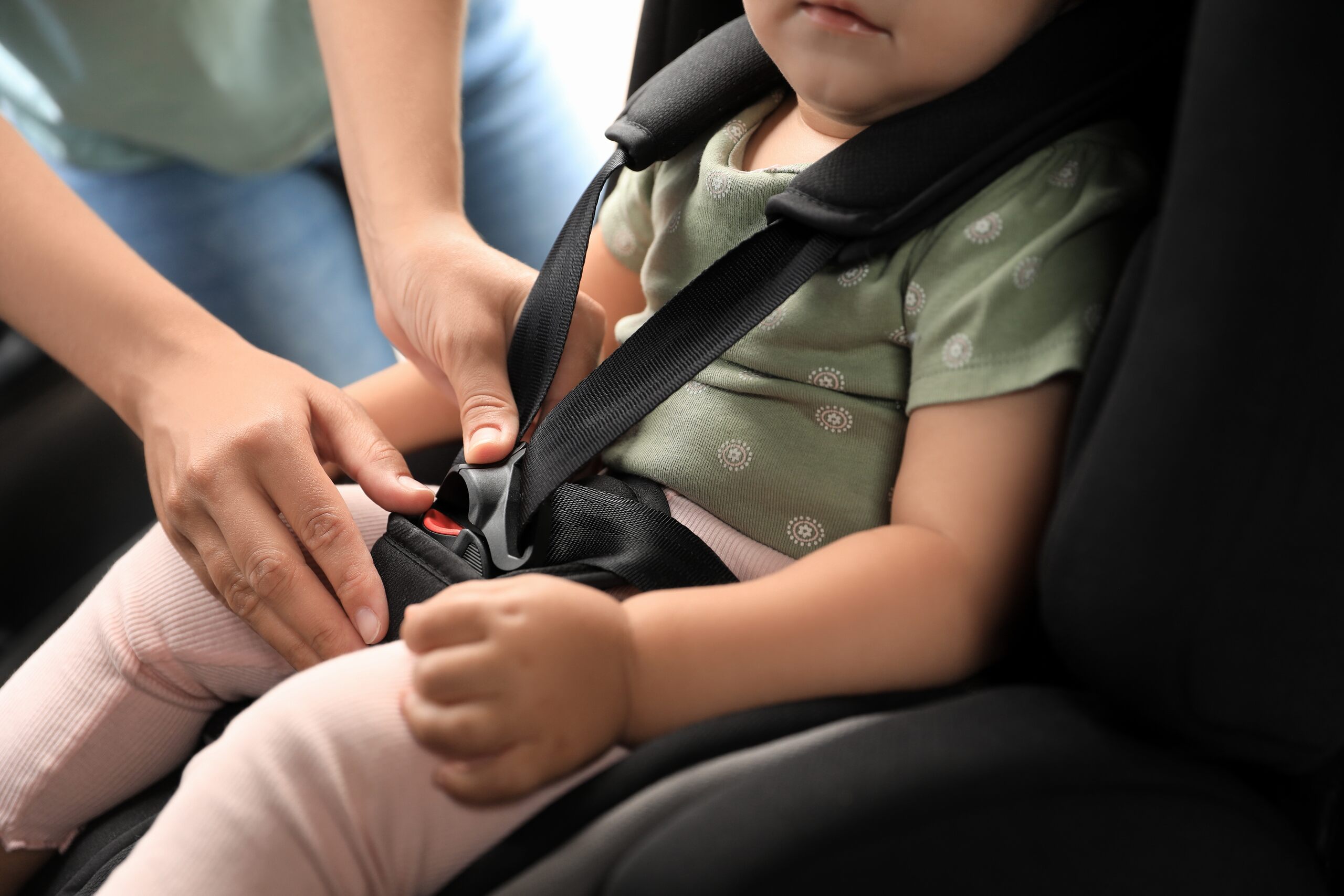 A parent securing a child in a rear-facing car seat to comply with Oklahoma car seat laws and height requirements for children under age 2.
