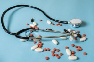 Stethoscope surrounded by scattered pills, representing the medication errors that can occur in patient care