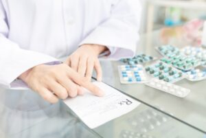 Pharmacist reviewing a prescription beside blister packs of medication, a key checkpoint where dispensing errors can occur
