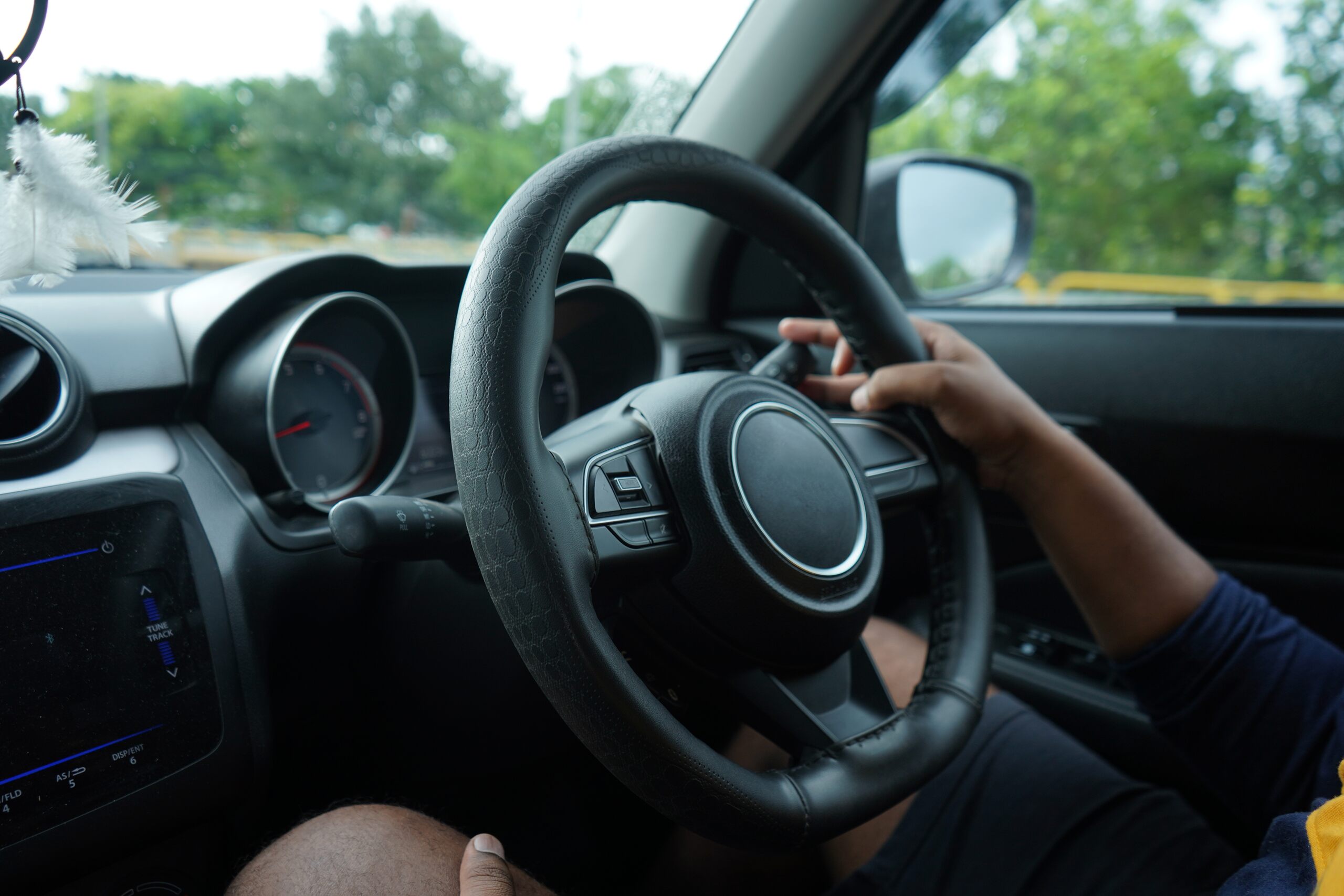 An interior view of a car showing a driver's hands gripping the steering wheel while operating a vehicle on the road, representing rideshare operations relevant to wrongful death after an Uber or Lyft accident in Oklahoma.