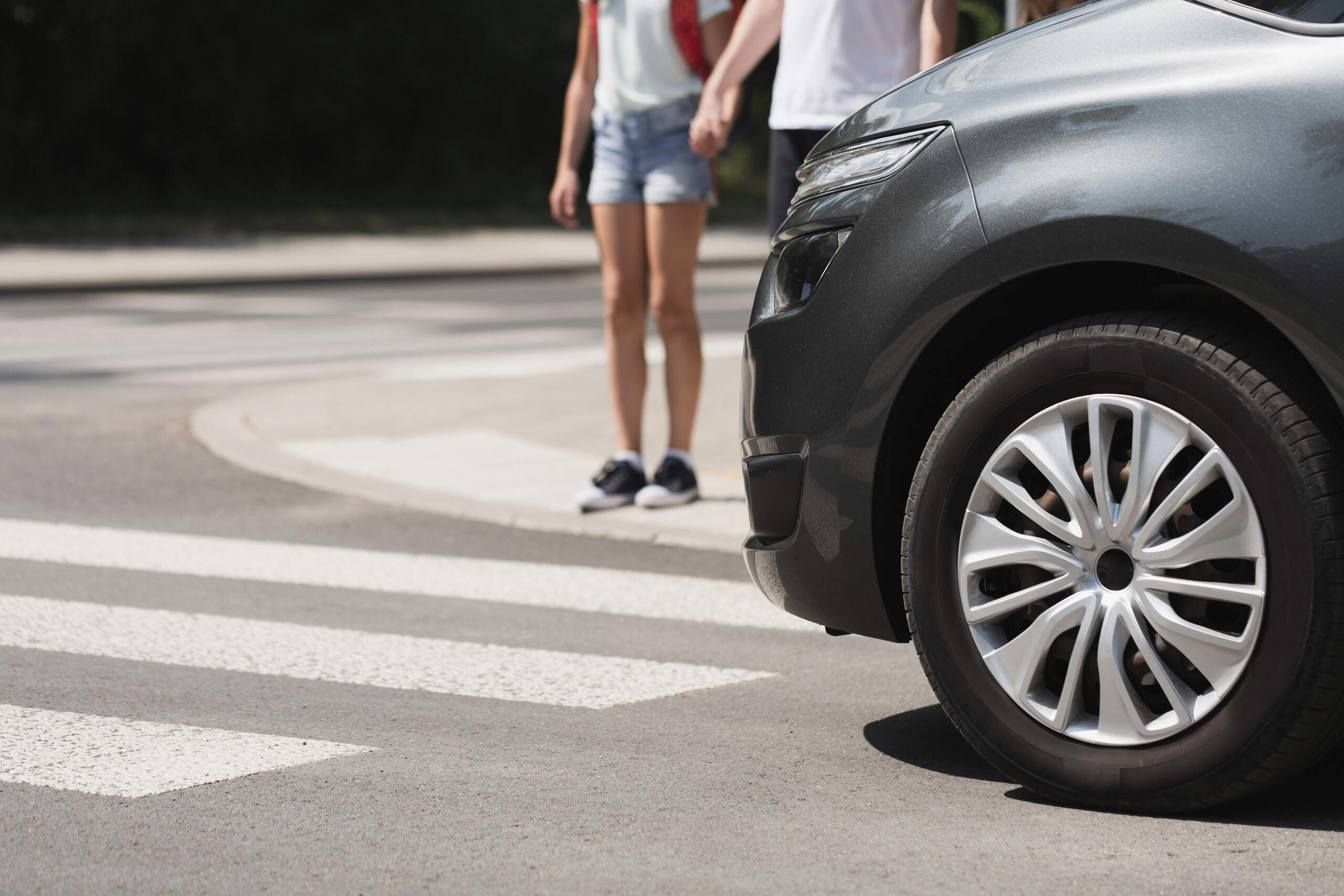 Vehicle stopped at a crosswalk as pedestrians walk nearby, illustrating what to do immediately after a pedestrian accident in Tulsa