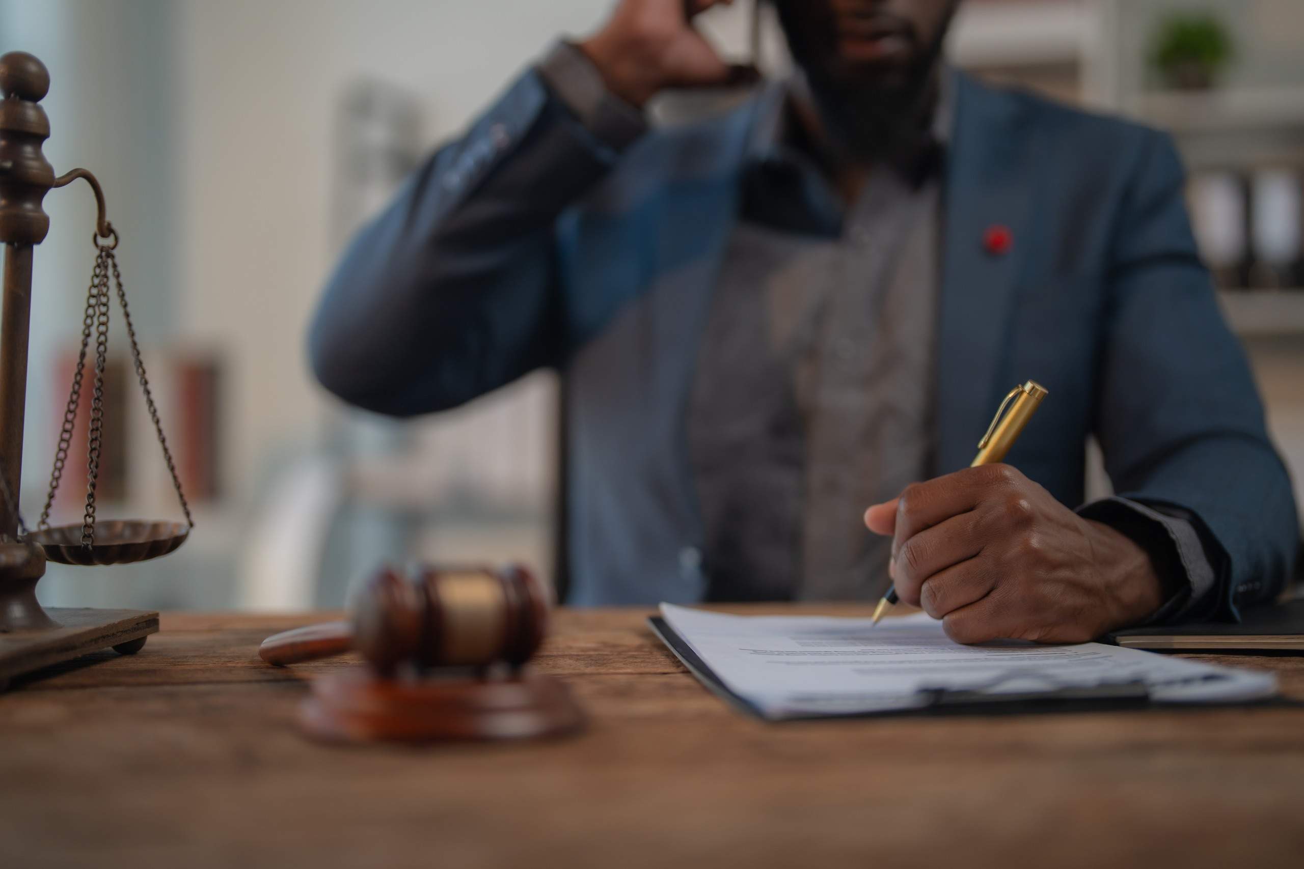Attorney discussing a personal injury case over the phone while drafting legal documents, showing when to hire a personal injury lawyer in Oklahoma.