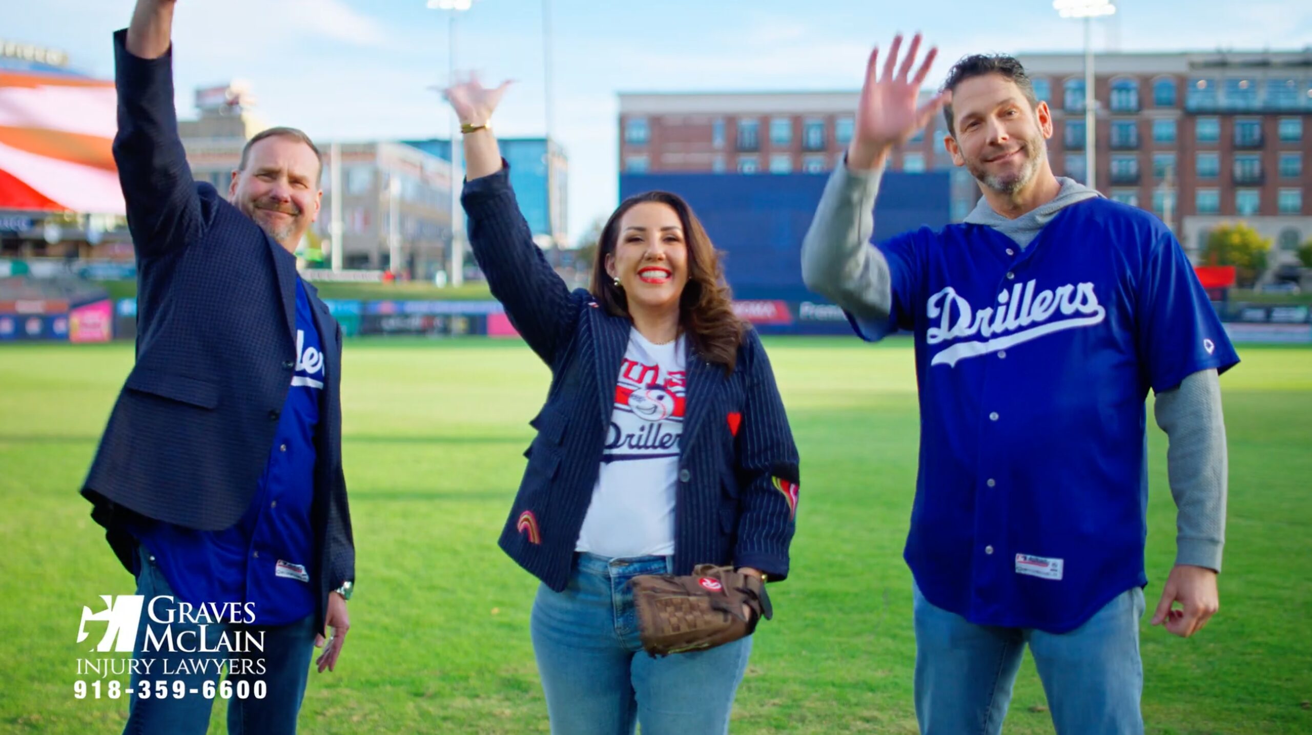 Tulsa personal injury lawyers in Drillers jerseys waving at ONEOK Field, showing community support in Oklahoma.