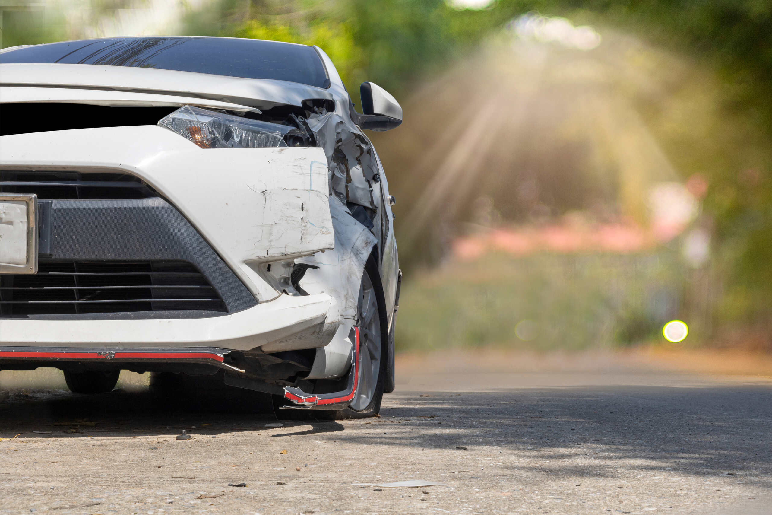 A white car with front-end damage after being forced off the road in Tulsa, illustrating a phantom vehicle case where no physical contact occurred.