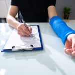 An injured person in Tulsa filling out a health insurance claim form after a rideshare accident involving complex TNC Act insurance periods.