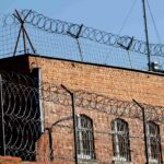 A brick building secured with heavy razor wire, symbolizing the punitive nature of damages intended to punish reckless drunk driving in Oklahoma.