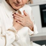 Woman clutching her chest in discomfort, a symptom often overlooked in female heart attack patients