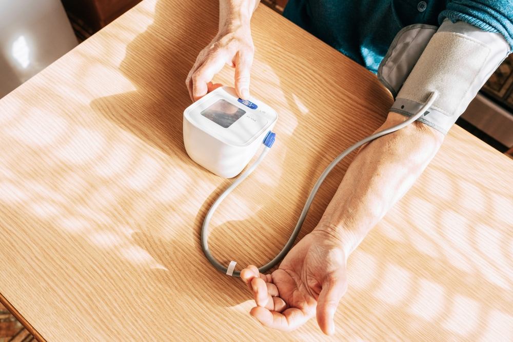 Person using a blood pressure monitor at home to check cardiac health