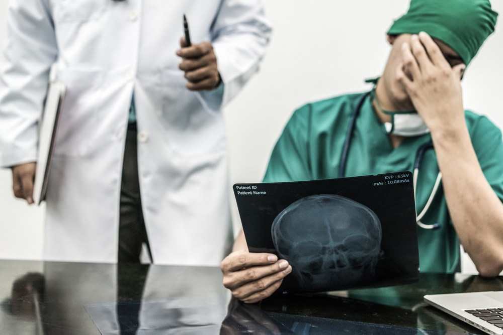 Medical staff reviewing a patient X-ray, one appearing distressed over the findings