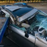 A severely damaged car with a smashed windshield on a tow flatbed shows severe vehicle loss when asking how long does a truck accident lawsuit take in Oklahoma.