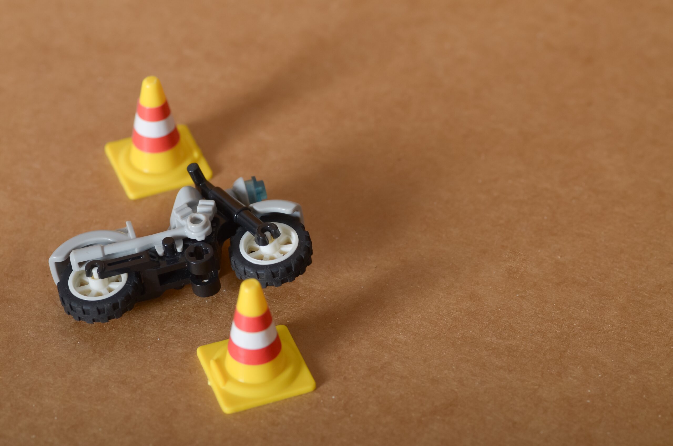 A toy motorcycle lies between small traffic cones illustrating accident scene concepts related to Oklahoma motorcycle helmet laws and how they affect your injury claim.