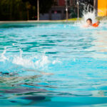 Swimmers splashing in an outdoor pool where understanding liability in swimming pool drowning and near-drowning claims in Oklahoma is essential.