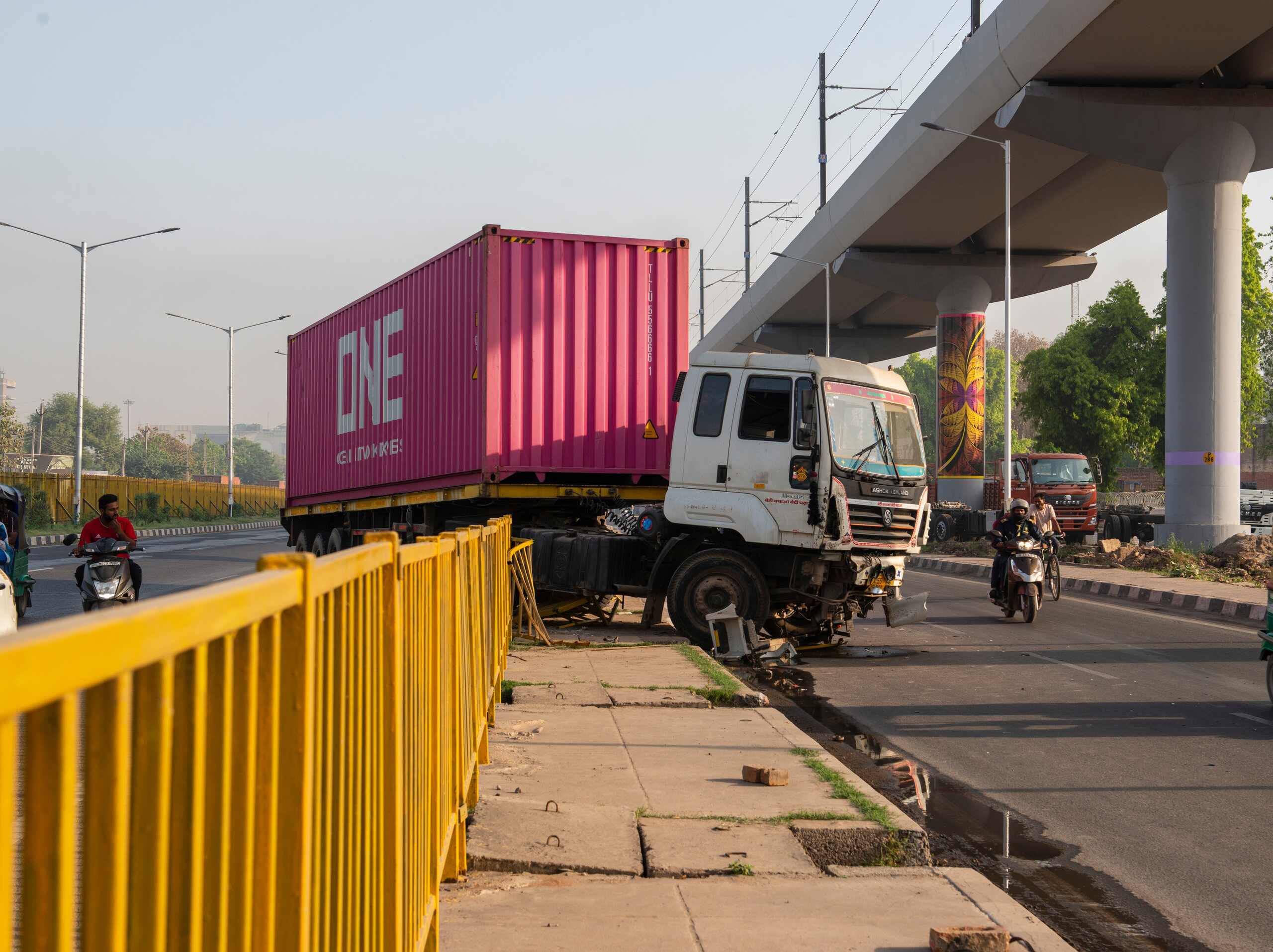 Semi truck carrying a pink cargo container crashed along a city roadway.